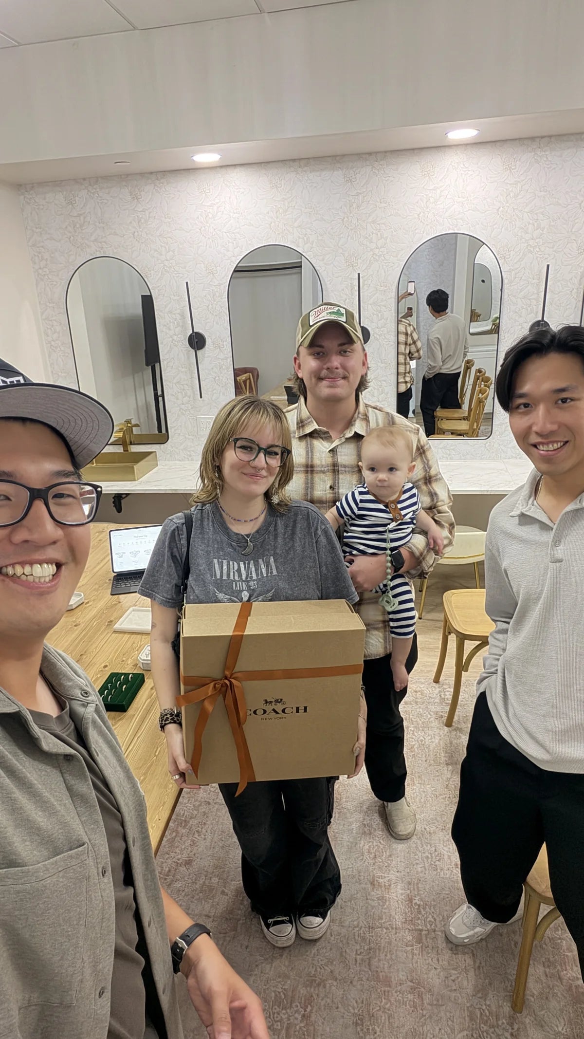 A couple and their baby with Beylora team members after receiving the Coach Chelsea giveaway prize