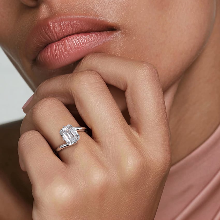Ring setting worn on the hand in white gold, shown with an emerald center stone