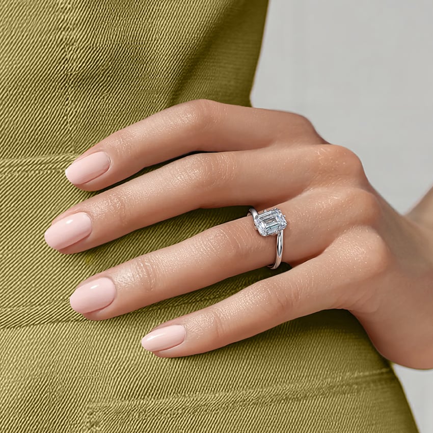 Ring setting worn on the hand in white gold, shown with an emerald center stone